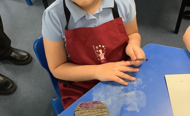 Image of We have been using clay in Art to create stamps. First, we flattened the clay and then used various tools to make imprints on it. We then painted the stamps and used them to print on our card. We are really impressed with how they turned out!